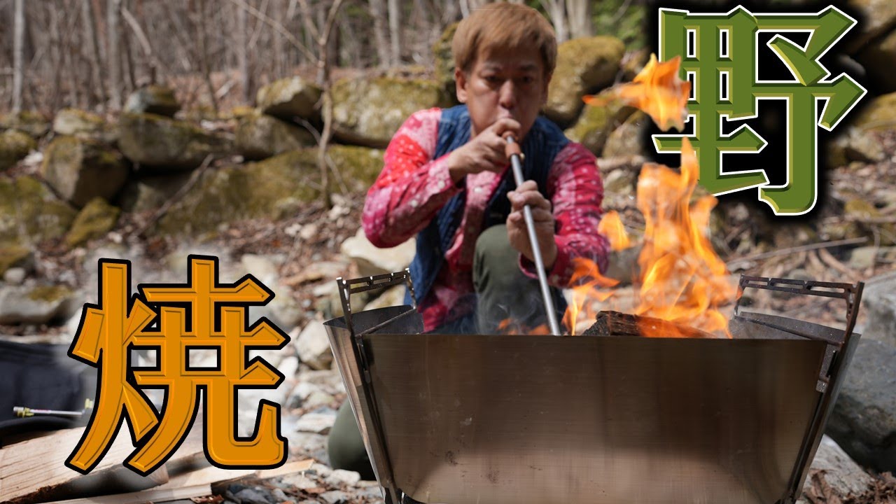 野で火をおこし肉を焼くため山に入るひとりキャンプ　　　　　　　　　　　　　　　　　　　　　　　　A man makes a fire in the mountains and grills meat.